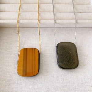 Vintage tiger eye and obsidian stone pendant necklaces with copper chains on display