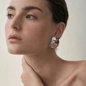 Boucles d'oreilles abstraites en forme d'escargot argenté poli portées par un mannequin
