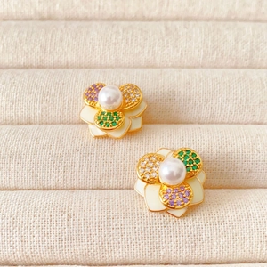 Elegant gold camellia stud earrings with white enamel petals and central pearl inlay