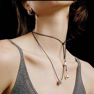 Minimalist black rope necklace with hollow silver ball pendant and metallic accents