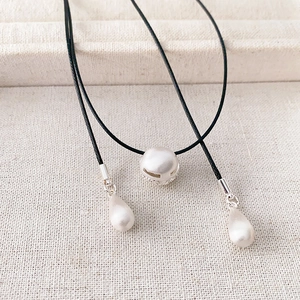 Minimalist black cord necklace featuring a large round pearl and teardrop accents