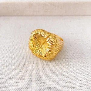 Dettaglio macro dell'anello quadrato dorato con trama a raggiera e stile vintage raffinato