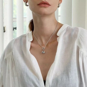 Minimalist silver padlock necklace and twisted hoop earrings set on a female model