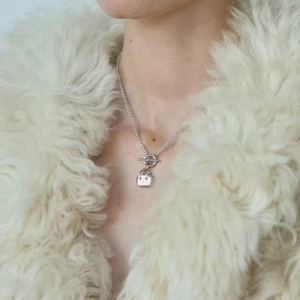 Detail view of mini handbag pendant on silver OT clasp necklace with plush faux fur coat