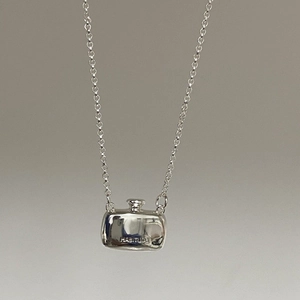 Close-up of minimalist silver perfume bottle pendant with HABITUDE engraving