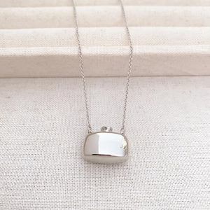 Detailed close-up of a silver flask-shaped perfume bottle pendant on an O-chain necklace