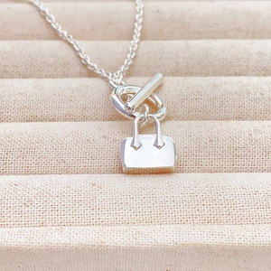 Minimalist silver perfume bag pendant necklace with OT toggle clasp on jewelry tray