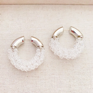 Handmade crystal beaded silver hoop earrings for women on beige fabric background