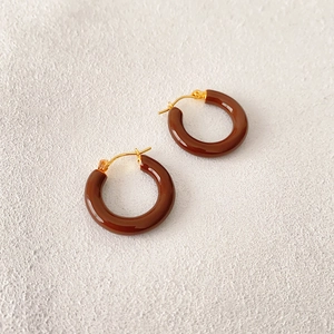 Close-up of dark brown enamel hoop earrings with polished gold-plated metal hardware