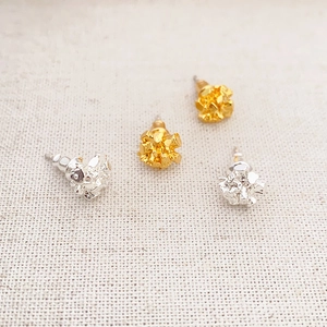 Gold and silver irregular cube stud earrings with natural texture on beige fabric
