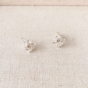 Irregular cube silver cluster stud earrings on a textured fabric background