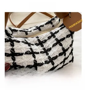 Détail du tissage en tweed à carreaux noir et blanc et de la poignée en cuir marron