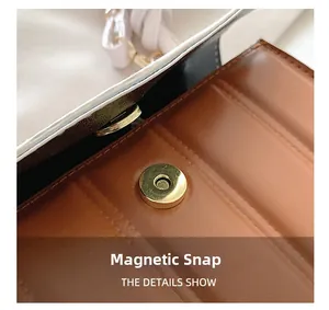 Detailed macro view of a brown leather bag featuring a gold magnetic clasp and vertical stitching