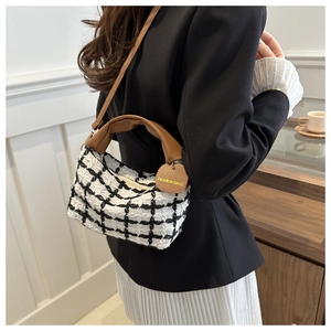 Vue détaillée du sac en tweed à carreaux noir et blanc avec poignées en cuir marron