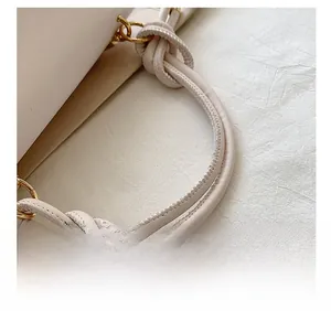 Detail showing the knotted leather handle and gold D-ring hardware of this stylish handbag