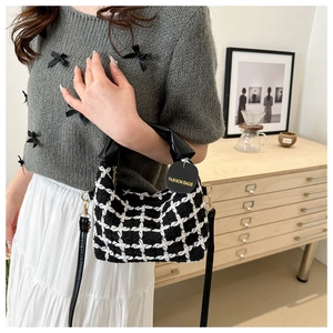 Gros plan d'un sac à main en tweed à carreaux noir et blanc porté avec une tenue chic