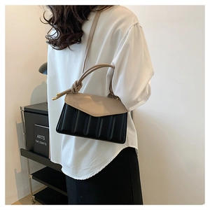 Detail view of contrast quilted mini square bag with top handle and shoulder strap worn by model