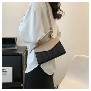 Detail of contrast flap shoulder bag featuring vertical quilted texture and knotted strap