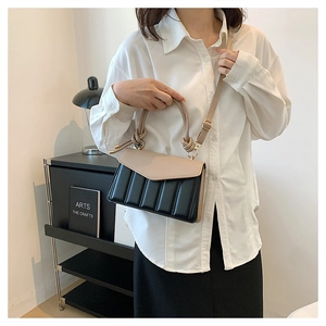Detail view of the black and beige contrast shoulder bag with vertical quilting and straps