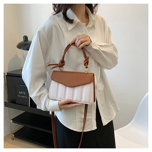 Detail of color-block crossbody bag featuring brown leather flap and cream pleated texture