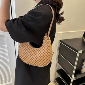 Französische Halbmond-Satteltasche mit braunem Monogramm-Muster an einer Frau getragen