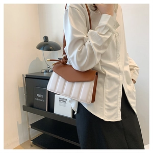Detail of contrast leather shoulder bag featuring vertical quilted texture and knotted strap