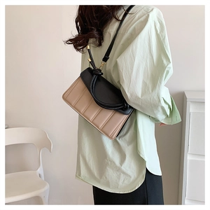 Contrast color crossbody bag detail showing contrast flap and fine vertical stitching
