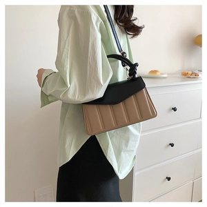 Detail of contrast color crossbody bag with quilted beige body and black knotted handle