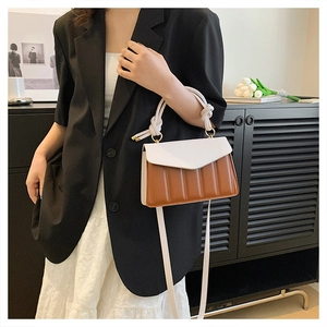Detail of color-block crossbody bag with vertical quilting and twisted rope handle