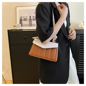 Detail of color-block shoulder bag with white flap and textured brown leather body
