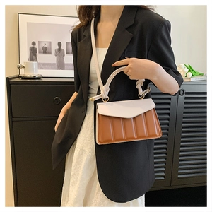 Detail of color-block PU leather handbag with pleated texture and knot handle design
