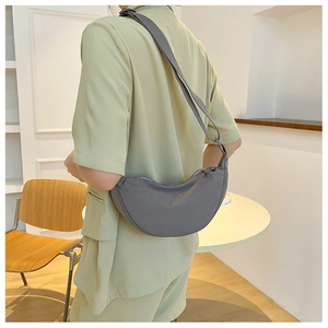 Detail view of dark grey crescent shoulder bag showing matte nylon texture and size on model