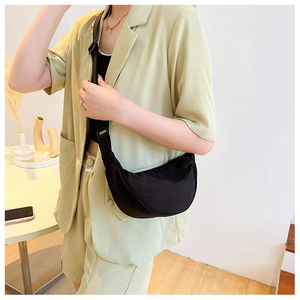 Adjustable strap on a black nylon crescent bag shown in a real-life wearing scenario