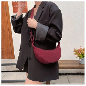 Close-up of a burgundy crescent moon crossbody bag with nylon fabric and wide strap