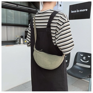 Detail view of crescent crossbody bag with adjustable wide strap on a person