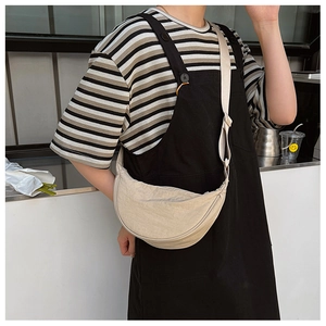 Beige crescent-shaped nylon hobo bag on a model in a minimalist indoor setting
