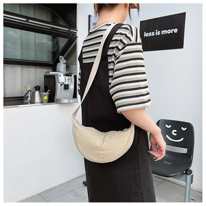 Detail of minimalist beige nylon crescent bag featuring adjustable strap and smooth texture