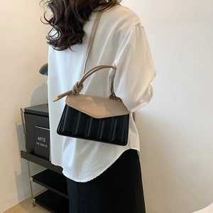 Contrast color leather handbag in beige and black with quilted texture and handle