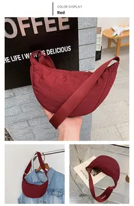 Detail view of a vibrant red nylon crescent bag with adjustable wide fabric shoulder strap