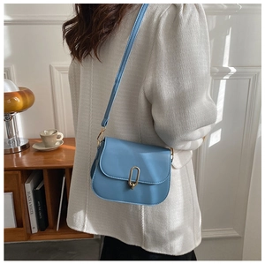 Lifestyle shot of light blue flap crossbody bag with a gold oval metal lock and strap
