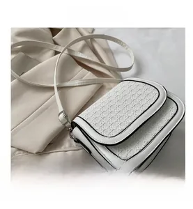 Close-up of white woven pattern crossbody bag with black contrast piping and metal clasp