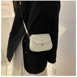 Minimalist white leather crossbody bag with golden horseshoe buckle worn by model