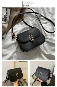 Detail view of black matte leather crossbody bag with gold U-shaped buckle and strap