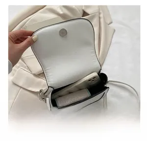 Internal capacity of the white saddle bag showing space for a smartphone and lipstick