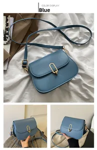 Detail view of a blue smooth leather shoulder bag with a gold U-shaped twist lock