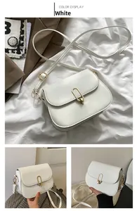 Detailed view of white leather crossbody bag with distinctive gold oval metal buckle