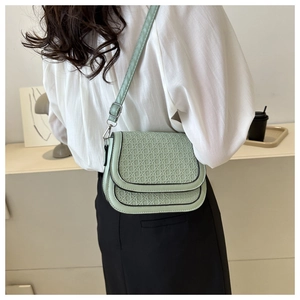 Detailed back view of a mint green woven saddle bag with adjustable strap on a model