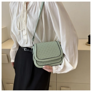 Detail of light green saddle bag showing 3D woven texture and black edge finish