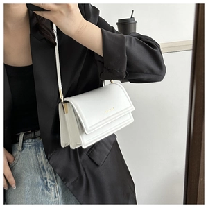 Detailweergave van een witte crossbodytas met gouden FASHION-belettering