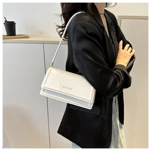 Witte lederen vierkante schoudertas met goud logo op een elegante zwarte satijnen blazer